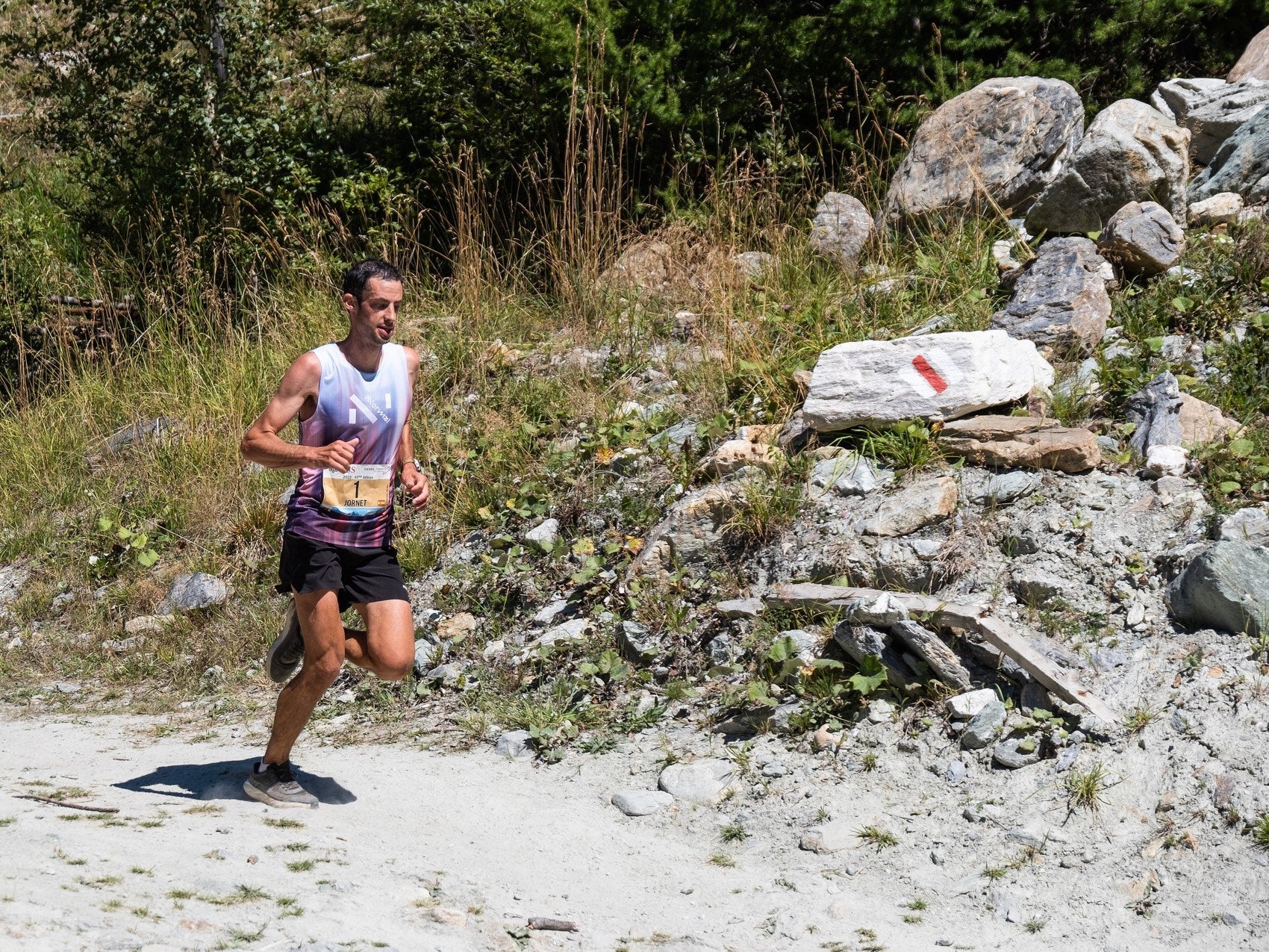 Kilian Jornet corriendo junto a una baliza blanca y roja del sendero en Sierre-Zinal 2022