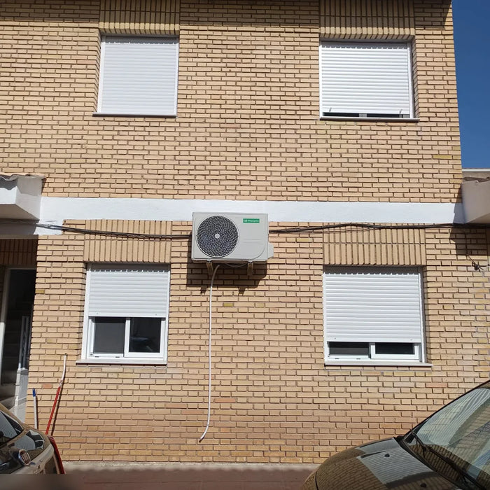 Unidad exterior de aire acondicionado Orbegozo instalada en la fachada de ladrillo de una vivienda del Valle del Almanzora