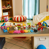 Colección completa de mini-modelos LEGO Classic 11045 expuesta en mesa de juego de habitación infantil: patín, conejo, sandía, casa, gato naranja, loro azul, coche y helado
