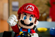 Detalle de la figura construible de Mario del LEGO 72037 con la gorra roja, el bigote y el brazo articulado al volante del Kart estándar