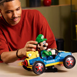 Adulto joven sonriendo mientras coloca la figura de Luigi en el kart LEGO Super Mario 72050 Mach 8 sobre mesa - set premium 18+ para fans de Mario Kart