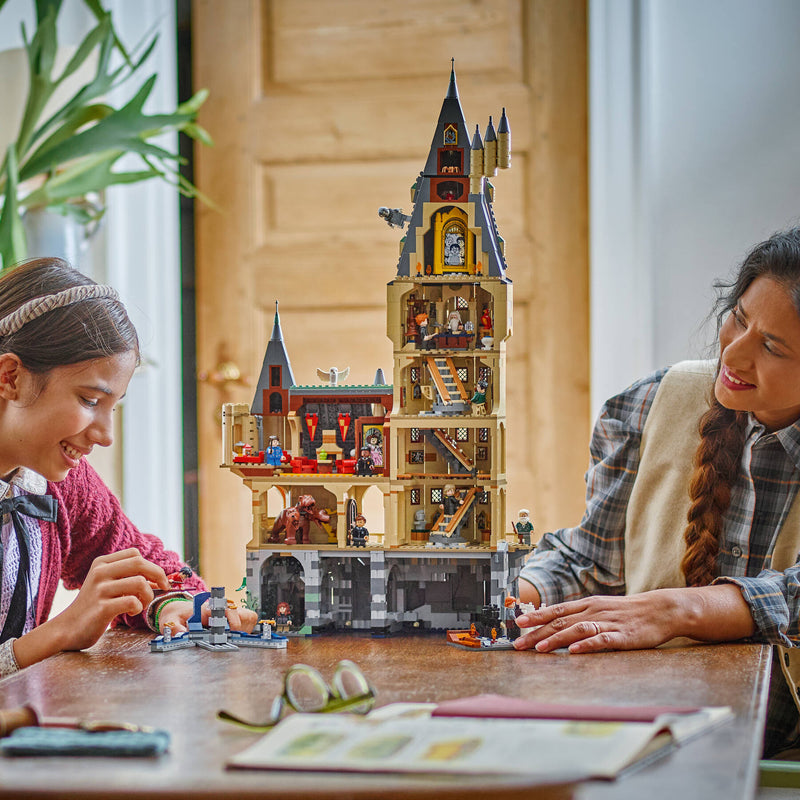 Dos personas jugando con la Torre Central de Hogwarts del set LEGO 76454 y sus 12 minifiguras