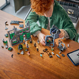 Niño pelirrojo construyendo el set LEGO Harry Potter 76471 Tiendas Mágicas Callejón Knockturn sobre mesa de madera, jugando con minifiguras y piezas del edificio