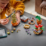 Niña construyendo el set LEGO Harry Potter 76474 Plantas de Herbología sobre mesa, manipulando la Mandrágora y los Geranios Colmilludos con tableta LEGO Builder