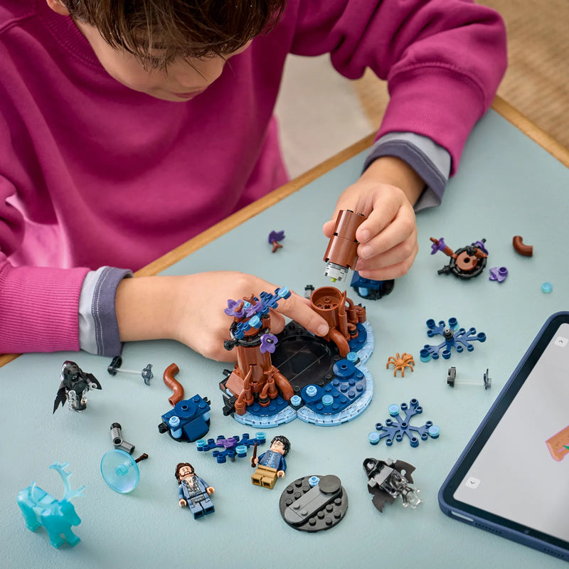 Niño construyendo el set LEGO Harry Potter 76475 Bosque Prohibido sobre mesa con árbol del set, dementores y piezas azules - guía paso a paso en tableta LEGO Builder