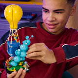 Adolescente sonriendo mientras juega con el set LEGO Fortnite 77080 Entrega de Suministros - globo amarillo y canasta azul con minifig Fishstick en habitación juvenil