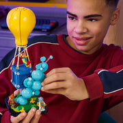 Adolescente sonriendo mientras juega con el set LEGO Fortnite 77080 Entrega de Suministros - globo amarillo y canasta azul con minifig Fishstick en habitación juvenil