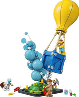Set LEGO Fortnite 77080 Entrega de Suministros montado: globo aerostático amarillo con canasta azul, nube de burbujas azules, minifigura Fishstick (pez naranja) en canasta, Astro Jack (astronauta blanco) y Gingerbread Raider sobre plataforma verde con accesorios