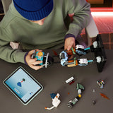 Niño con gorro azul construyendo el mecha LEGO Fortnite 77081 KIT vista cenital - tableta LEGO Builder, brazo del mecha en proceso y partes del torso azul