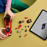 Niña construyendo el LEGO Speed Champions 77261 Ferrari 499P vista cenital sobre mesa amarilla con tableta LEGO Builder y piezas rojas del Hypercar