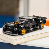 LEGO Speed Champions 77262 Ken Block Ford Mustang Hoonicorn V1 expuesto sobre tabla de madera junto a cojín naranja - perfil del muscle car con compressor y stickers Hoonigan