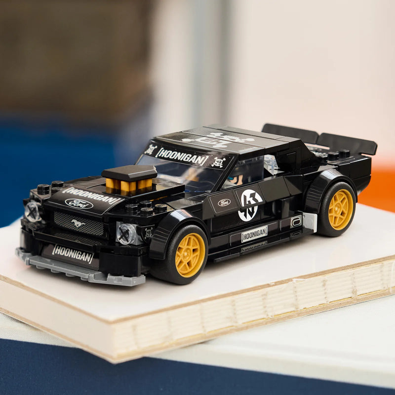 LEGO Speed Champions 77262 Ken Block Ford Mustang Hoonicorn V1 expuesto sobre tabla de madera junto a cojín naranja - perfil del muscle car con compressor y stickers Hoonigan