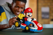 Adulto construyendo LEGO Mario Kart 72037 con figura Mario en kart estándar rojo sobre mesa
