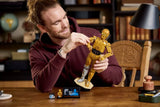 Adulto construyendo LEGO Star Wars C-3PO 75398 con figura dorada articulada sobre mesa de madera
