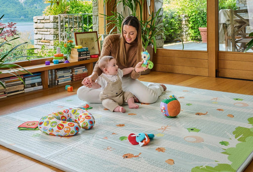 Bebé jugando sobre alfombra de juegos Chicco 2 en 1 reversible con ilustraciones estimulantes, base antideslizante en relieve y funda de transporte incluida
