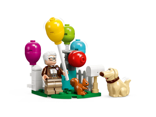 Escena LEGO Up 43217 con Carl, Russell, Dug y globos multicolores en jardín con valla blanca
