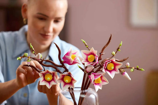 Mujer ajustando LEGO Botanicals 11510 magnolias rosa blanco
