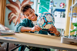Niño mostrando LEGO 43019 balón fútbol construido mesa
