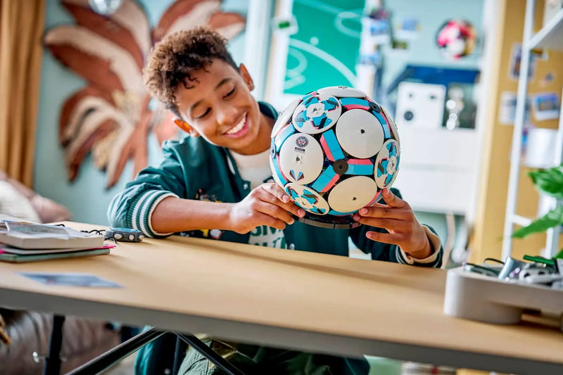 Niño mostrando LEGO 43019 balón fútbol construido mesa

