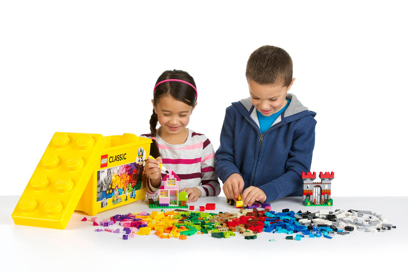 Caja de almacenamiento de plástico amarilla del LEGO Classic 10698 abierta, con las piezas y dos niños construyendo