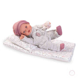 Muñeca Kika Lagrimitas Antonio Juan 11115 sobre su camita con gorrito rosa, pijama gris con gatito y chupete — vista lateral