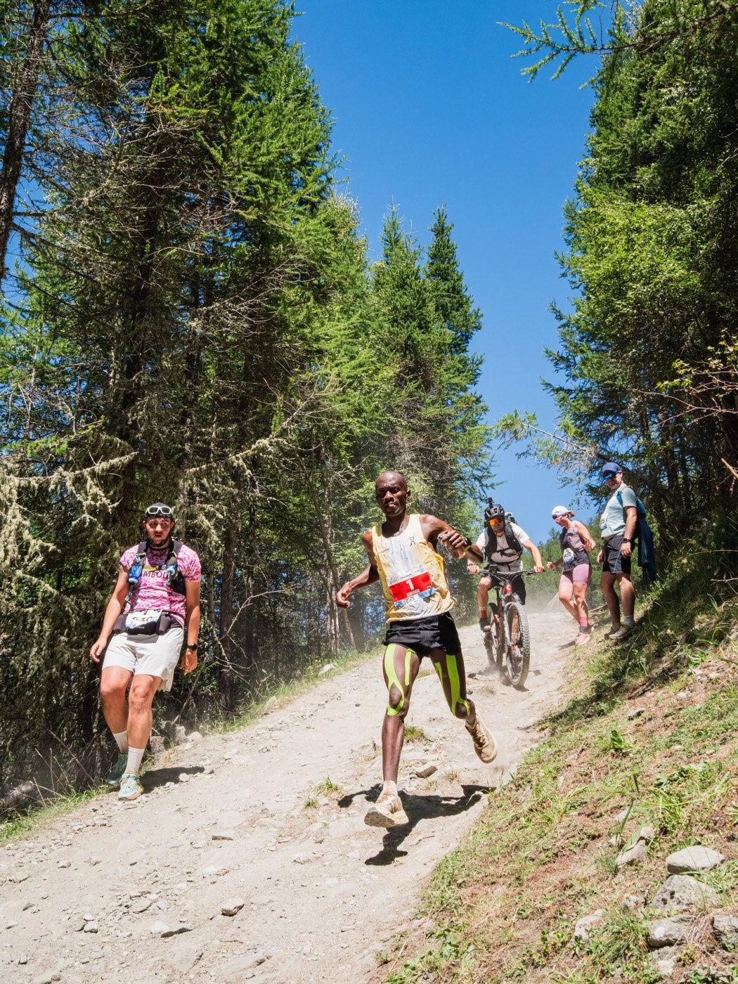 Philemon Kiriago bajando por una pista de tierra entre alerces en Sierre-Zinal 2026